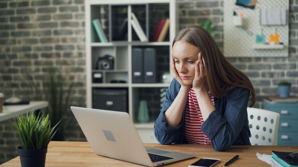 Mujer preocupada mientras trabaja con una laptop en un escritorio