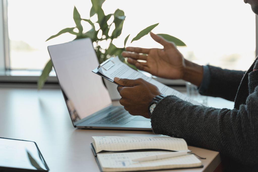 Profesional revisando un informe junto a una laptop y una libreta